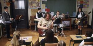 A School of Rock film still of a teacher playing guitar in a classroom