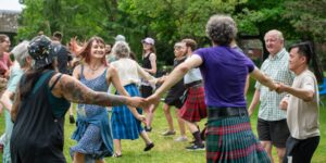 A group of people holding hands in a circle outdoors dancing