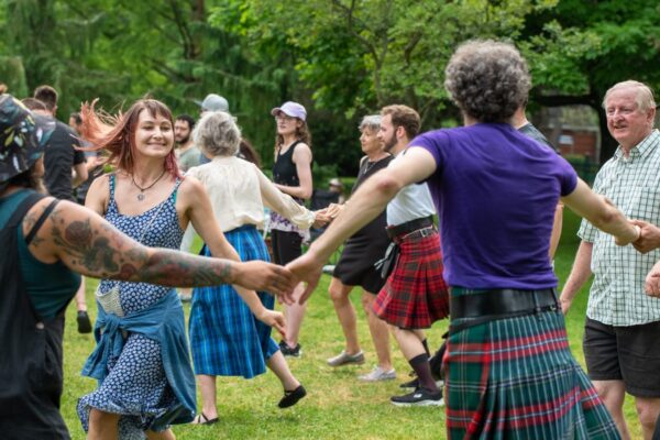 A group of people holding hands in a circle outdoors dancing