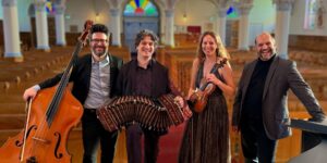 A group of four musicians posing with their instruments