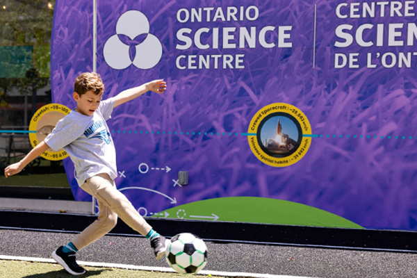 Kid kicking a soccer ball outside Ontario Science Centre at Harbourfront