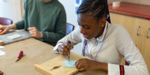 A student working on a block printing craft at a table