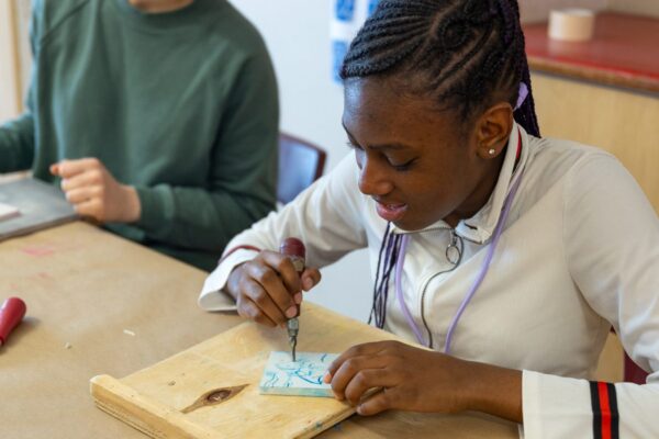 A student working on a block printing craft at a table