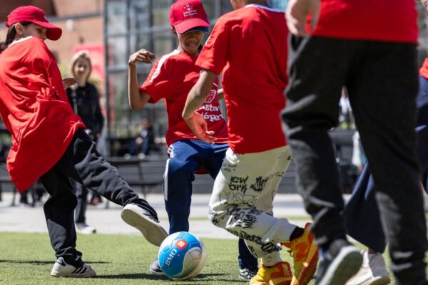 A group of kids playing soccer on an outdoor pitch