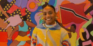 A person posing in front of a bright coloured background