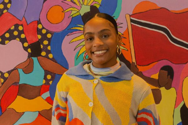A person posing in front of a bright coloured background