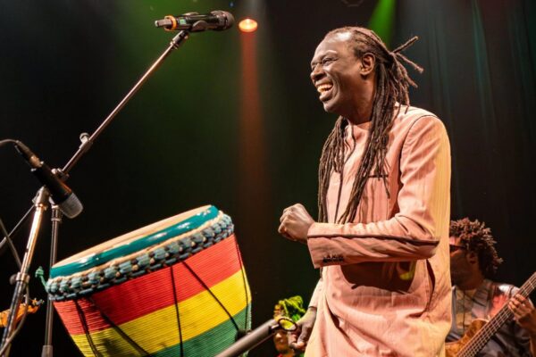 A musician performing on stage with a band and a percussion