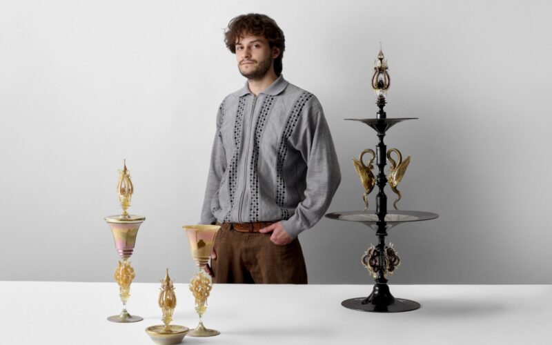 An artist posing with his glass work