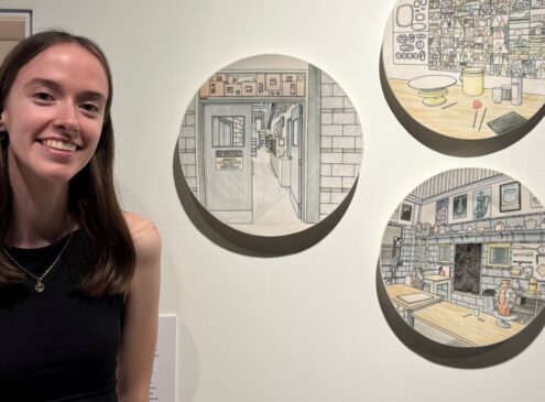 An artist poses in front of art work