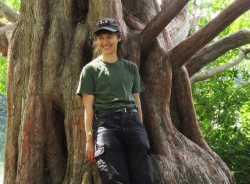 A person posing in front of a tree