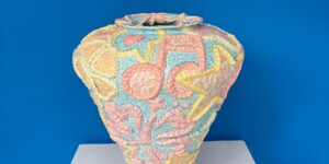 A colourful ceramic work against a bright blue background.
