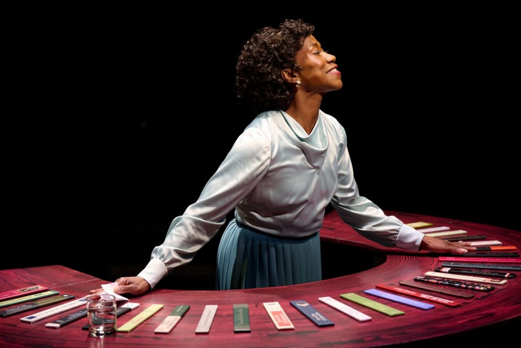Woman performing on stage next to a red table