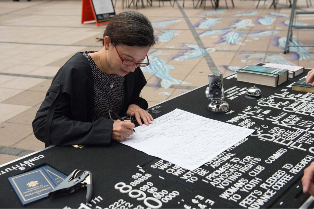 Woman writing on a piece of paper sitting at a table.