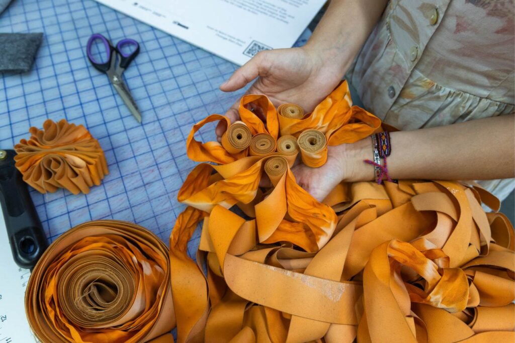 An artist holding orange ribbons working on an installation project