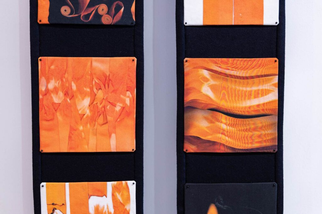 An artist holding orange ribbons working on an installation project