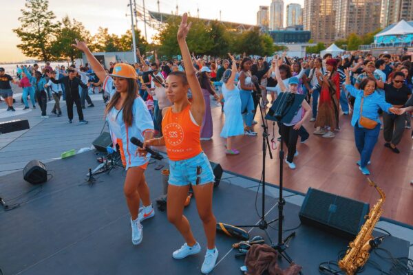 A crowd dancing with dance instructors outdoors