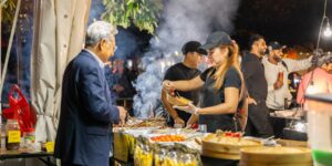 A market vendor serving skewers to a customer outside at night