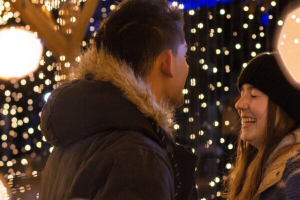 A couple laughing outside amongst holiday twinkling lights