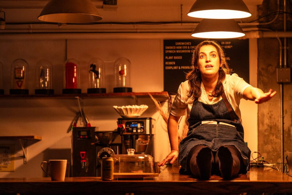 Woman performing in a cafe on stage in front of a theatre audience